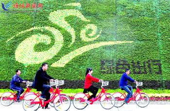 市民騎公共自行車路過市人民廣場(chǎng)一處花壇。記者 張馳